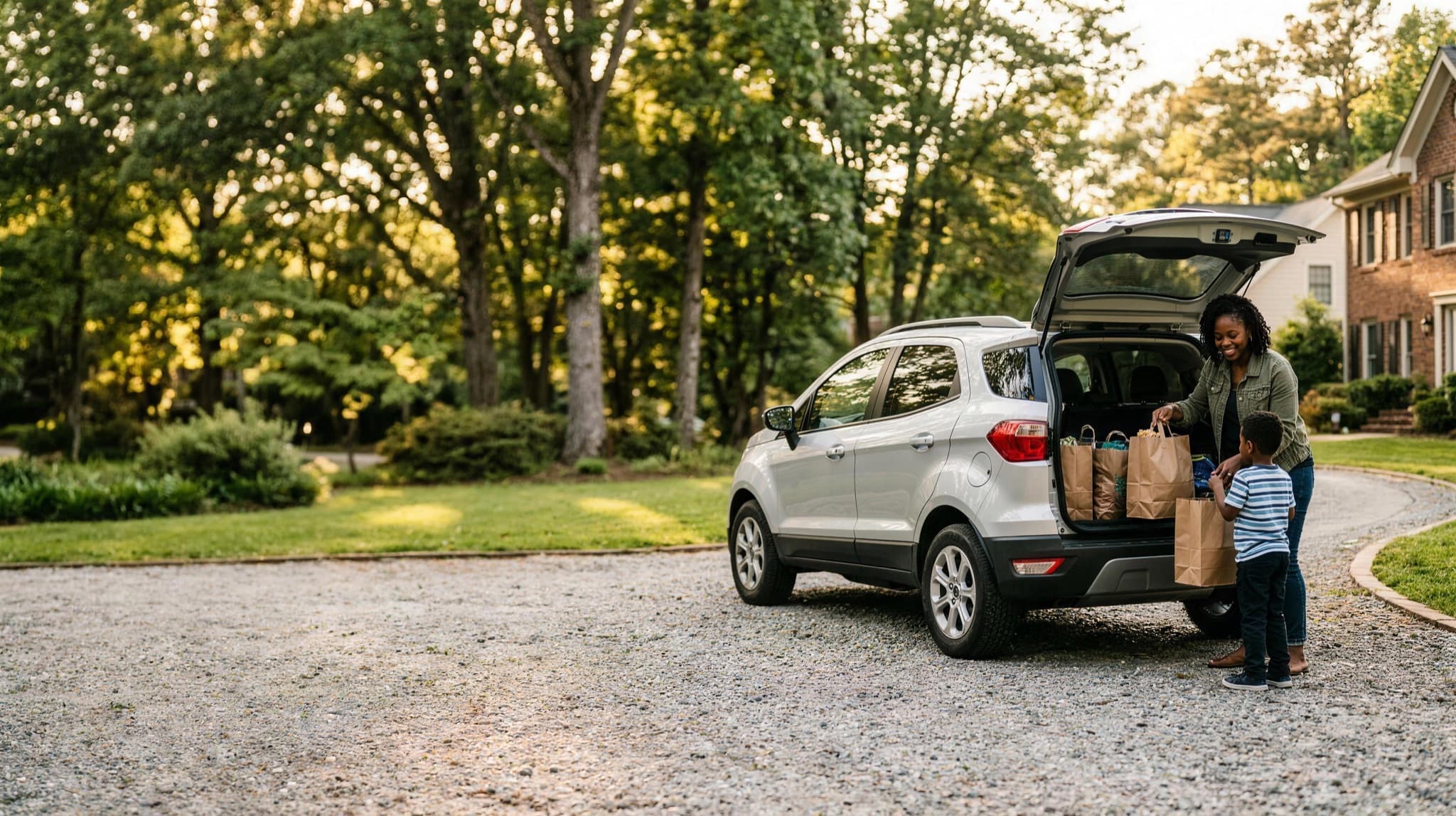 A mother and her son loading groceries into a rented SUV in their driveway